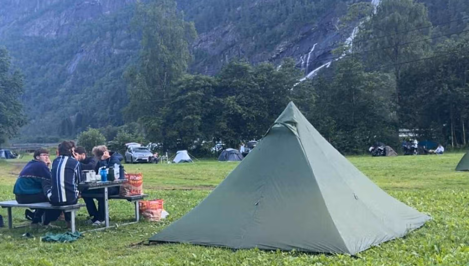 Familiencamping auf dem Hildal Camping, umgeben von grünen Bergen und rauschenden Wasserfällen.