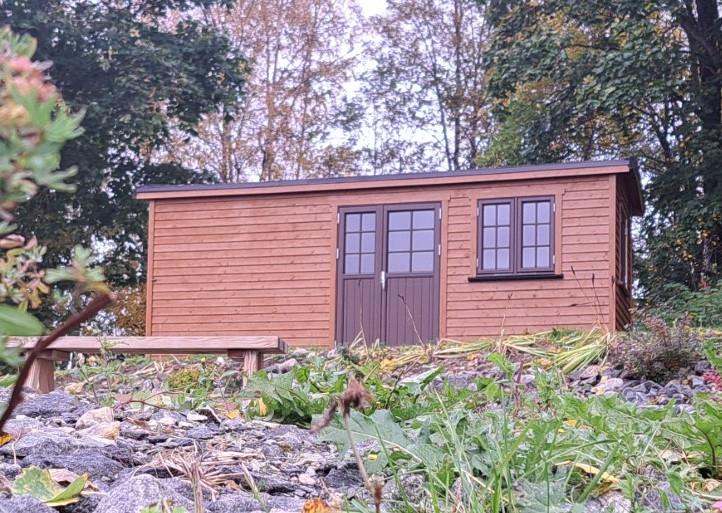 Exterior view of Gjeterhytta – small newly built wooden cabin with door and windows