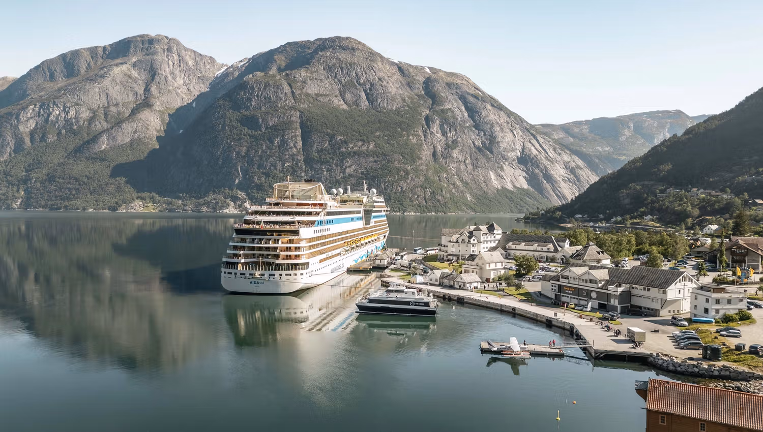 The harbour area with a cruise ship, a smaller vessel, a seaplane and people on the dock.