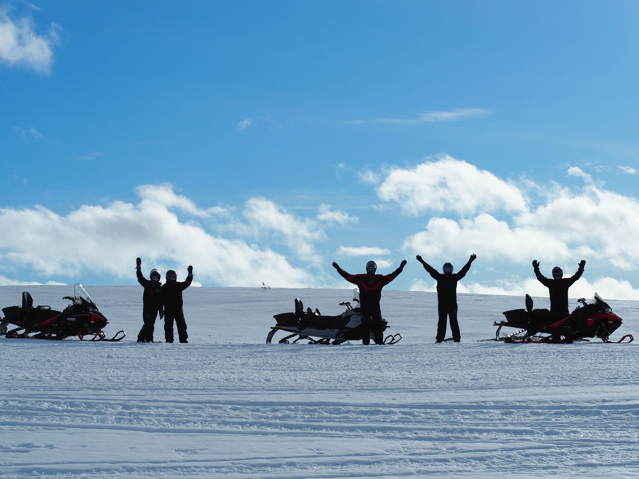 Groupe de personnes en tenue de neige célébrant sur un glacier sous un ciel bleu.