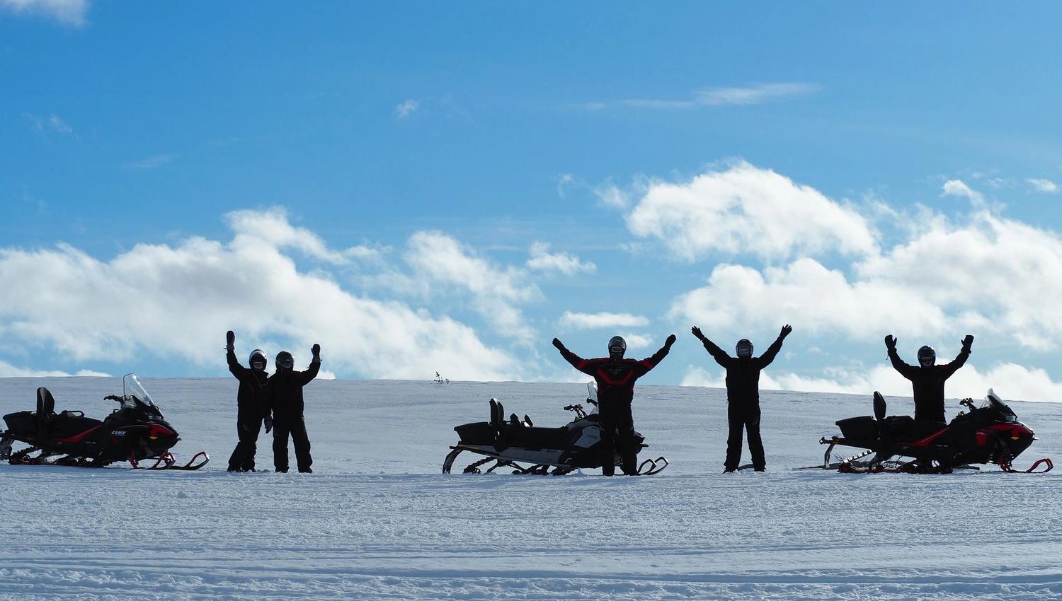 Groupe de personnes en tenue de neige célébrant sur un glacier sous un ciel bleu.