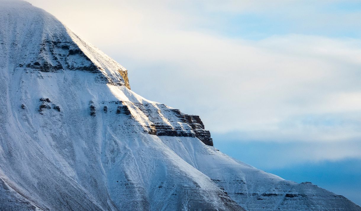 Et snødekt fjell med en skyet himmel i bakgrunnen