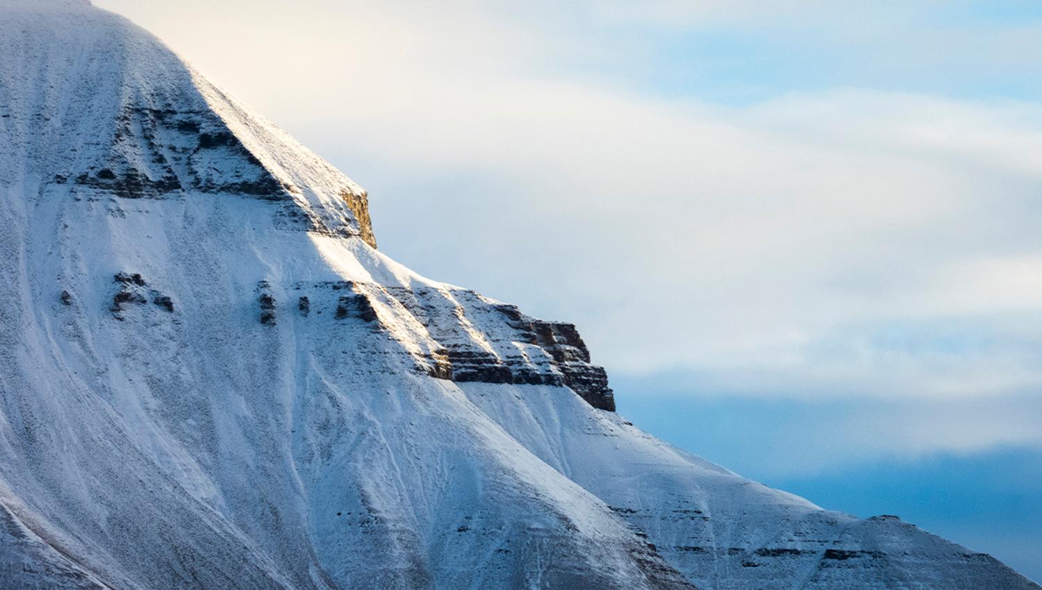 Et snødekt fjell med en skyet himmel i bakgrunnen