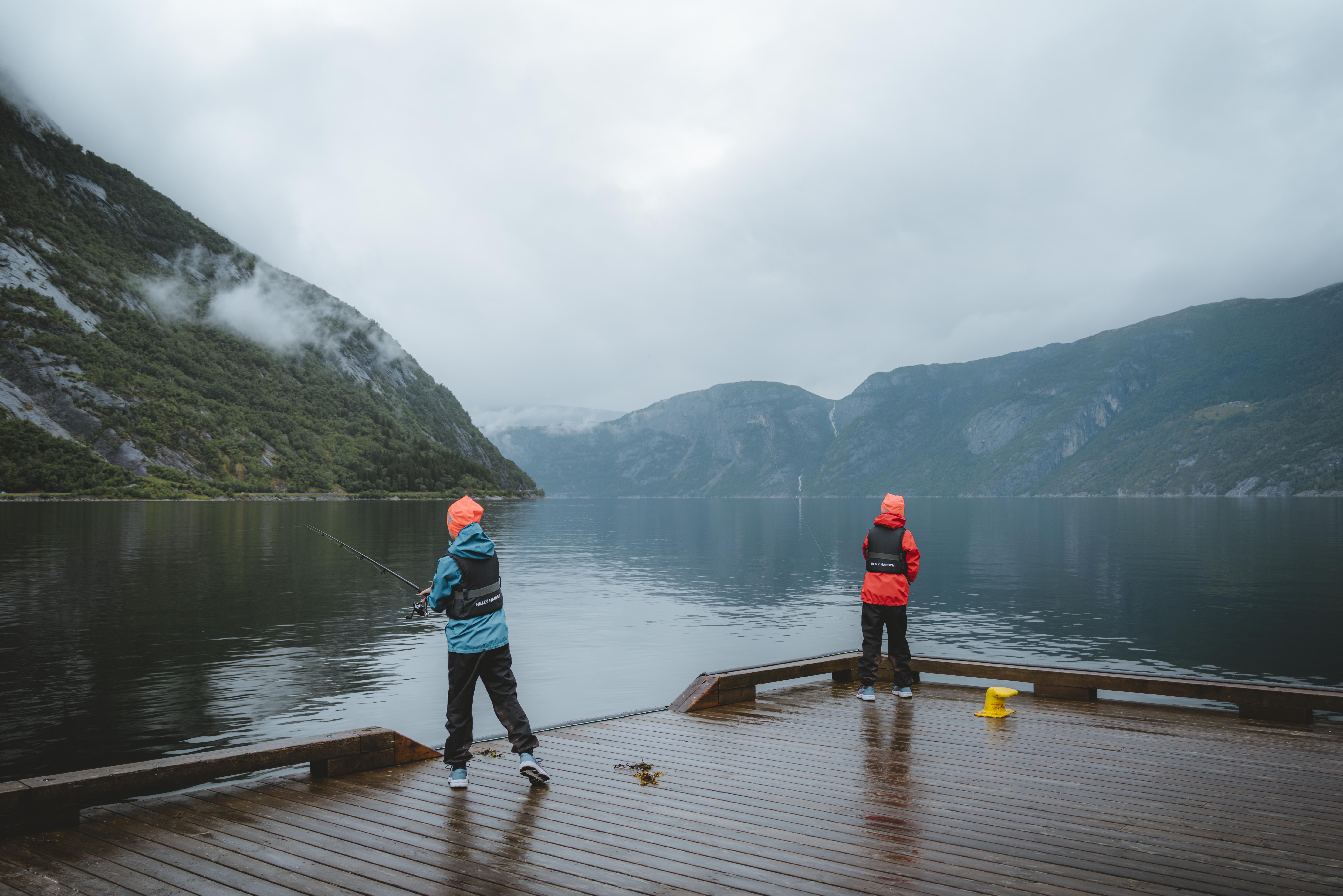 Two little boys fishing from the harbour in the rain.