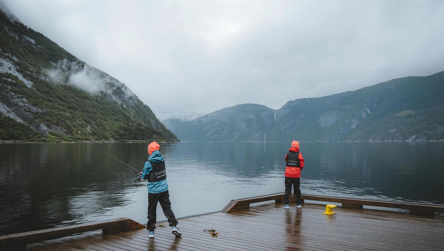 Two little boys fishing from the harbour in the rain.