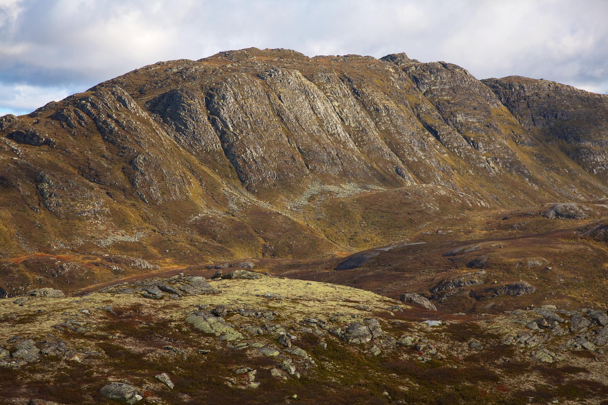 The summit point of Horntinden is located on a long mountain ridge, showing its steep flank to the photographer, while the trail leads up on the less 