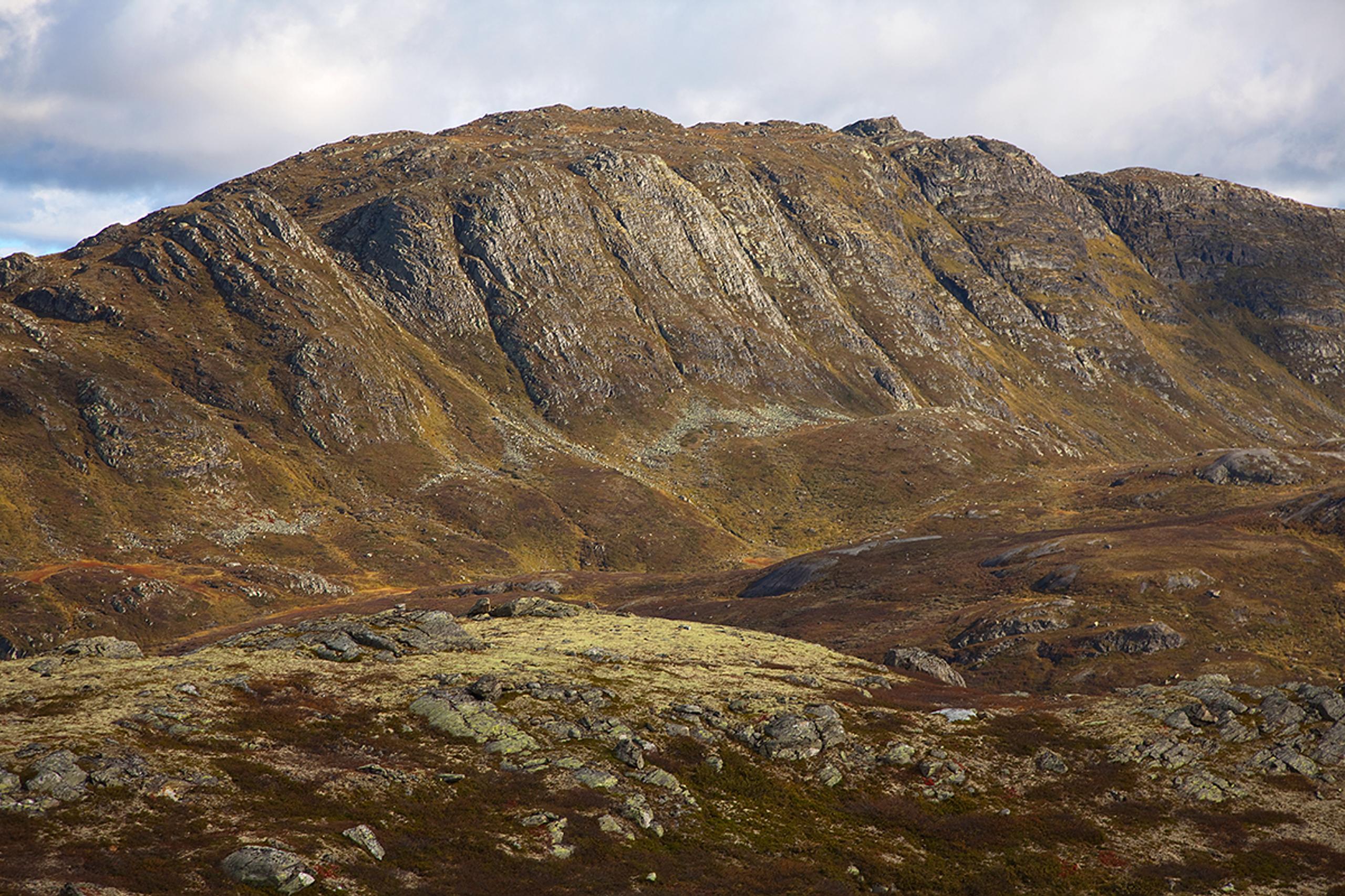 The summit point of Horntinden is located on a long mountain ridge, showing its steep flank to the photographer, while the trail leads up on the less 