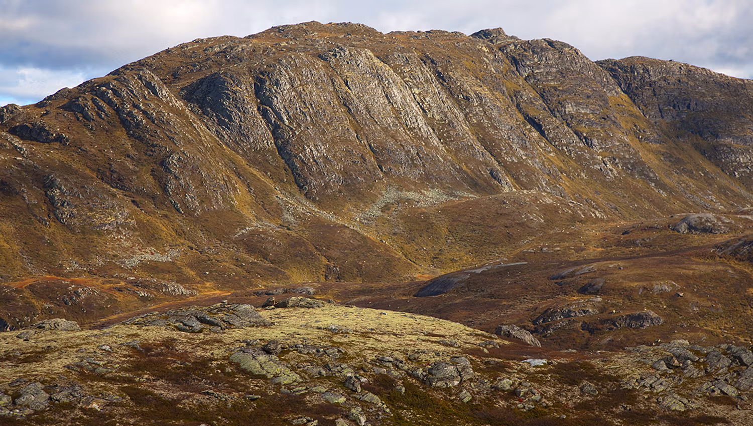 The summit point of Horntinden is located on a long mountain ridge, showing its steep flank to the photographer, while the trail leads up on the less