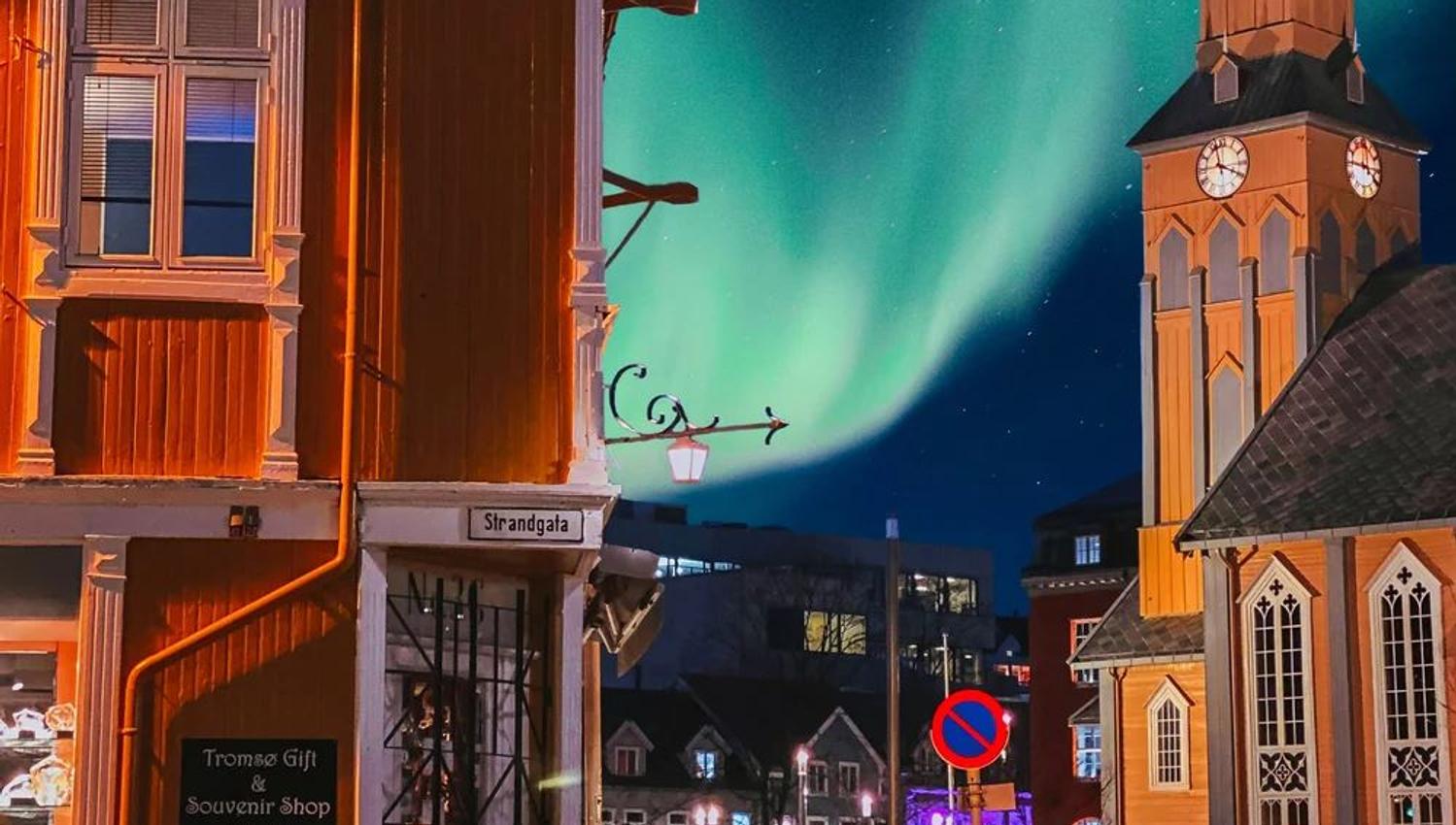 Northern lights above Tromsø Gift & Souvenir Shop with Tromsø Cathedral in the background.