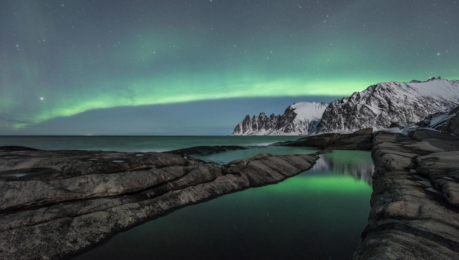 Northern lights above sea and mountains