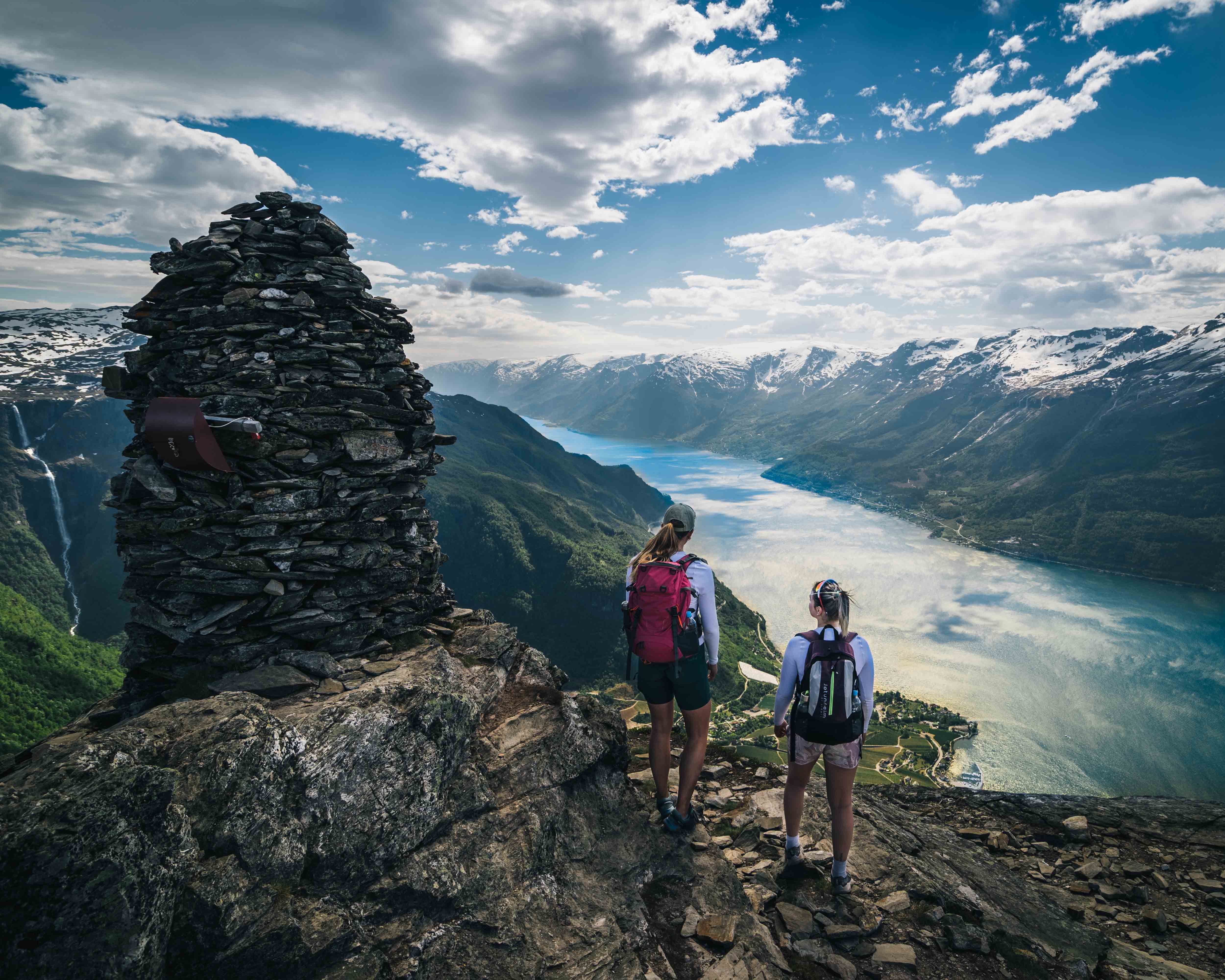 Turgåarar står ved ein varde på Dronningstien med spektakulær utsikt over fjorden.