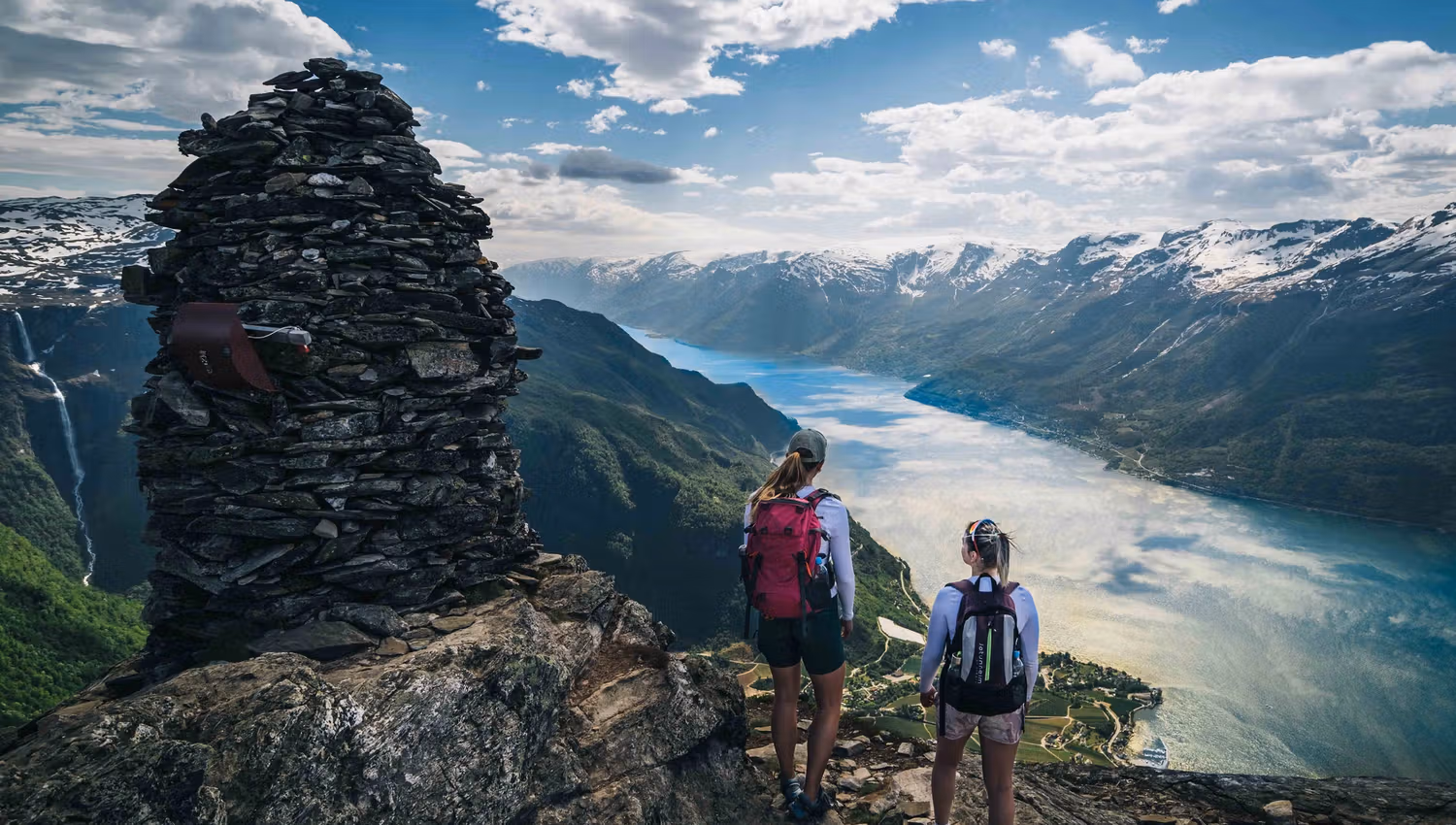 Turgåarar står ved ein varde på Dronningstien med spektakulær utsikt over fjorden.