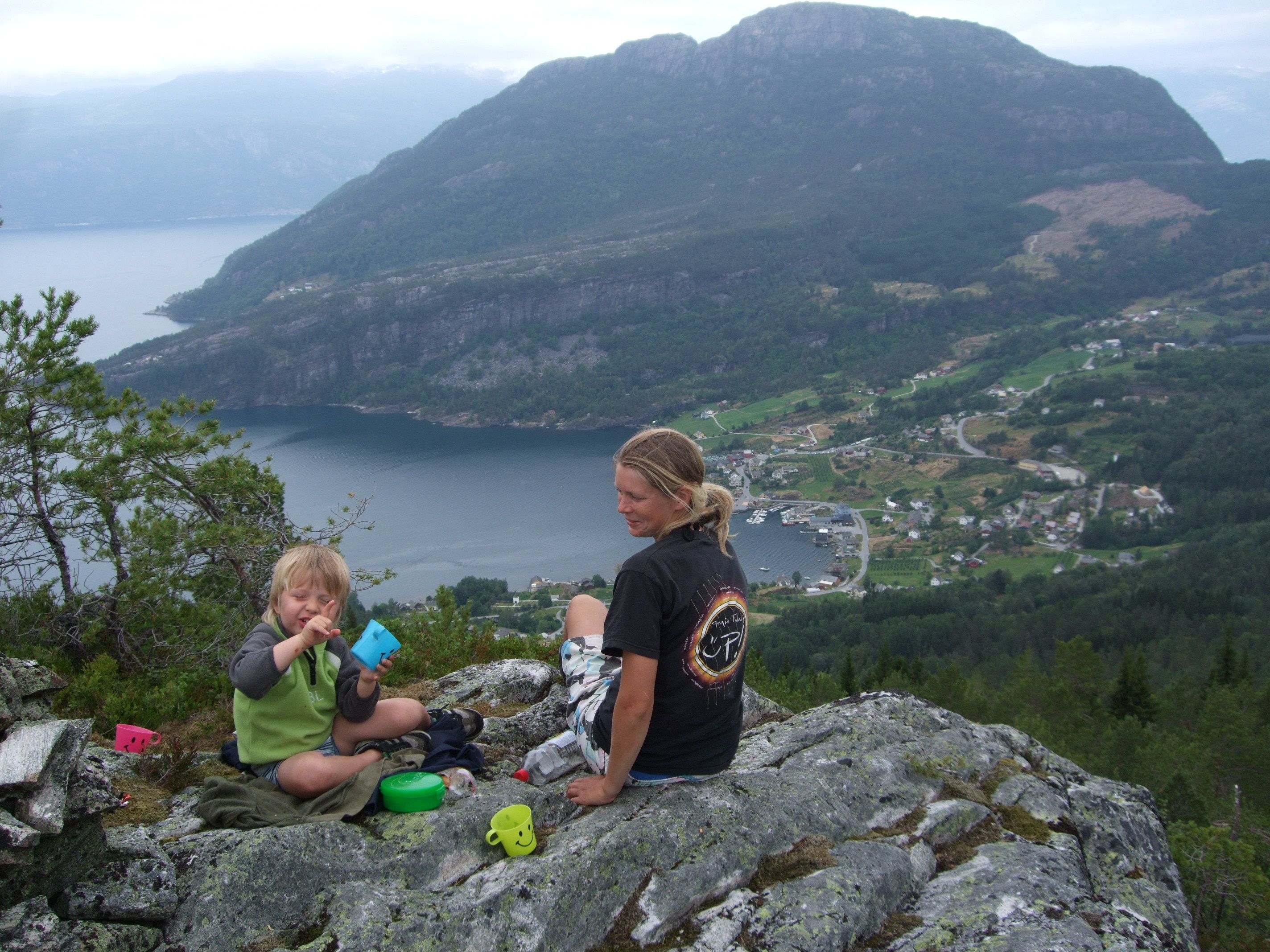 Family resting on the mountainside at Hereiane with a breathtaking view over the Hardangerfjord and the villages below.