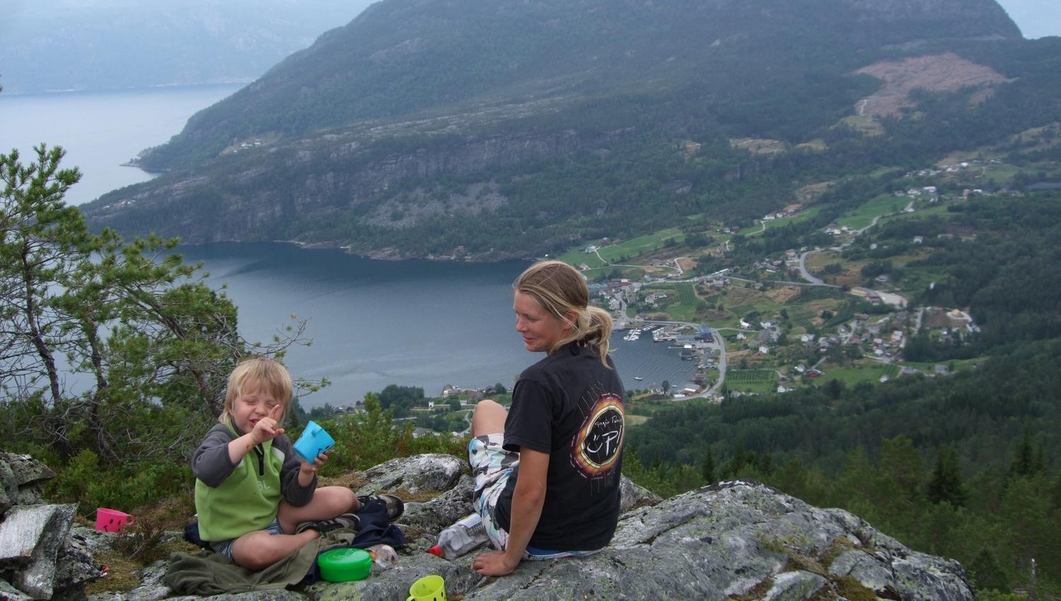 Family resting on the mountainside at Hereiane with a breathtaking view over the Hardangerfjord and the villages below.