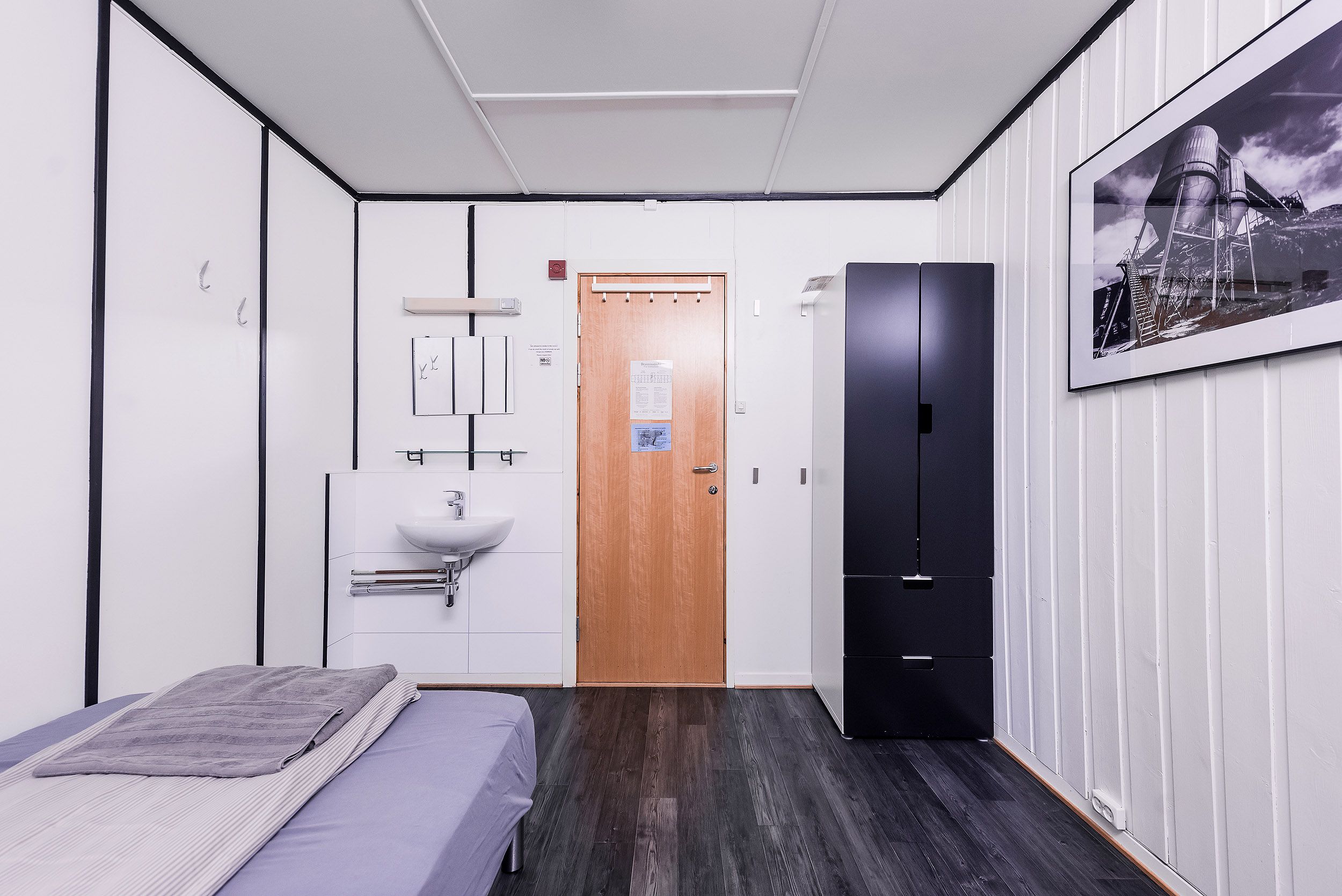 A bedroom with a single bed, a closet and a sink.