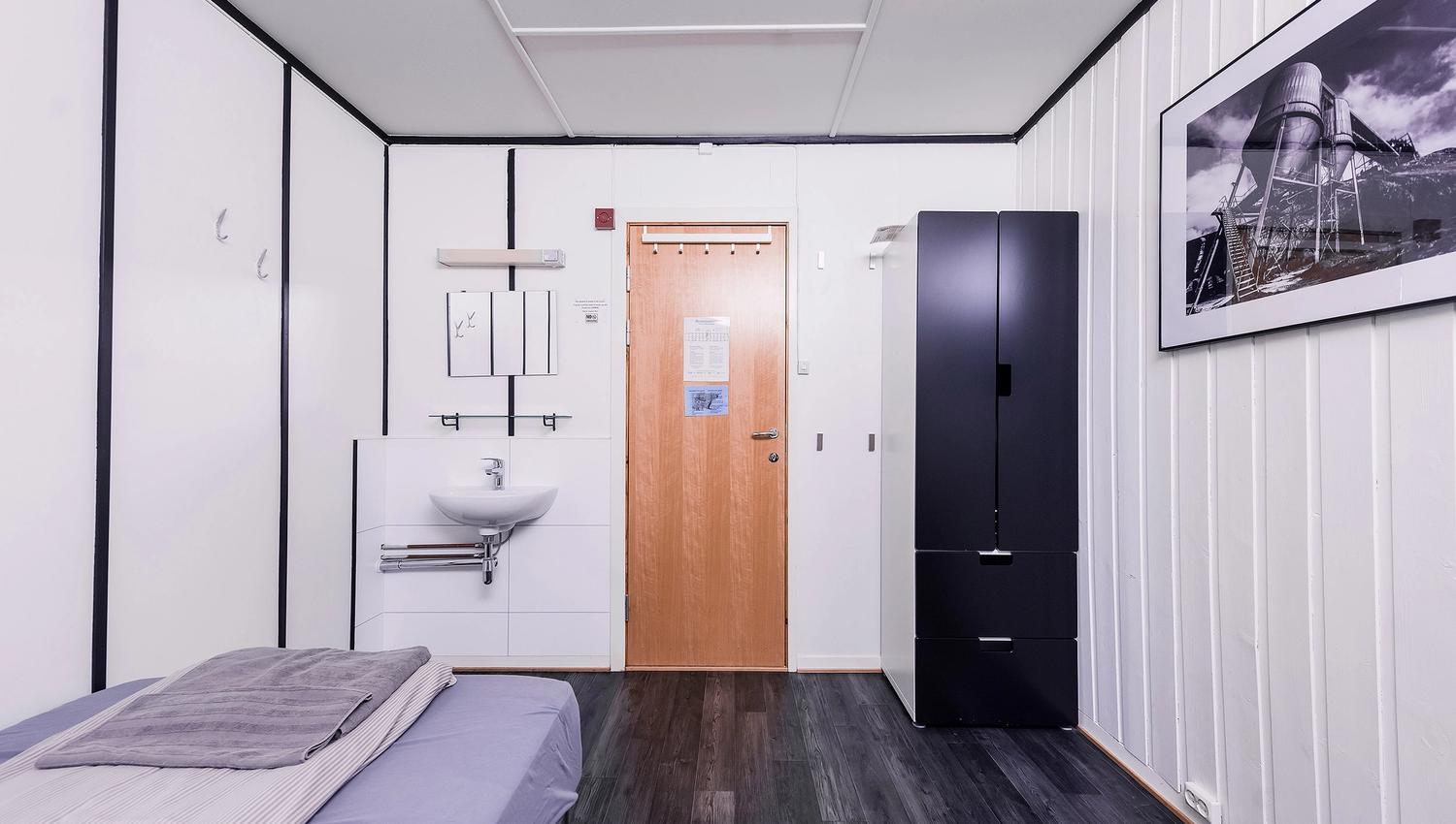 A bedroom with a single bed, a closet and a sink.