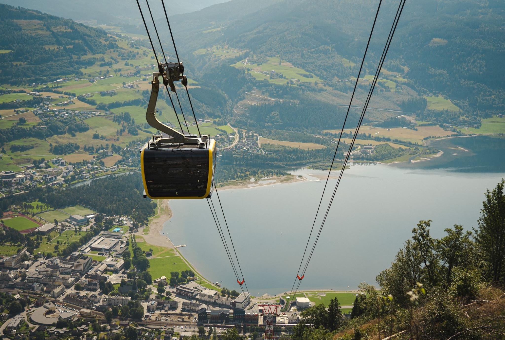 A gondola cabin ascending above Voss, with sweeping views of the town and lake far below.
