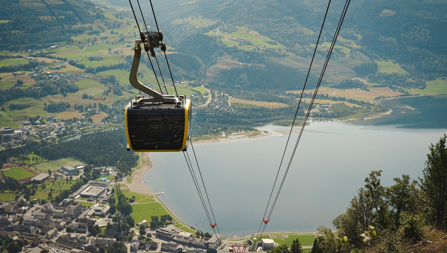 A gondola cabin ascending above Voss, with sweeping views of the town and lake far below.