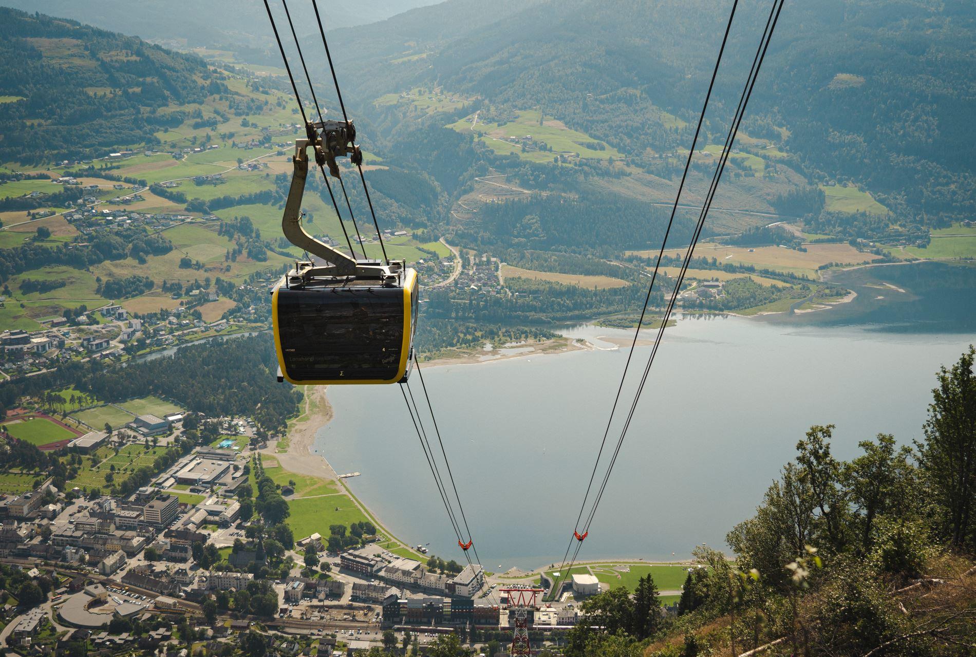A gondola cabin ascending above Voss, with sweeping views of the town and lake far below.
