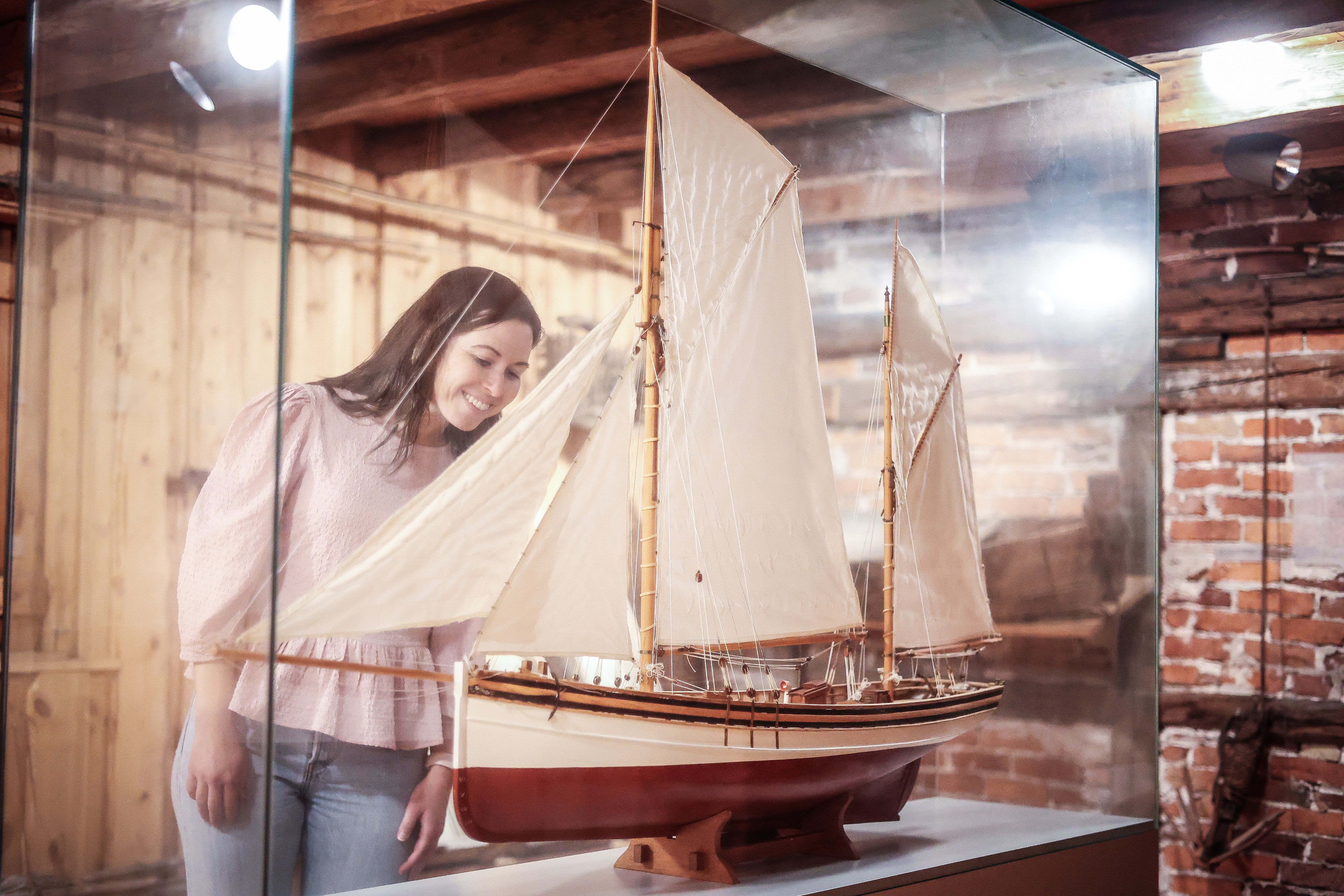 A smiling lady is looking at a miniature ship