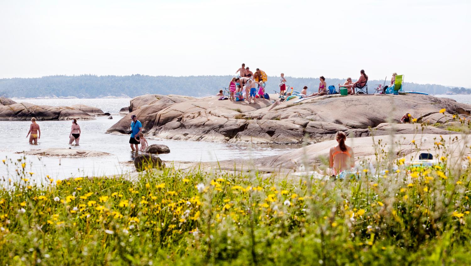 Dusa - mange mennesker som nyter solen ved havet. Foto.