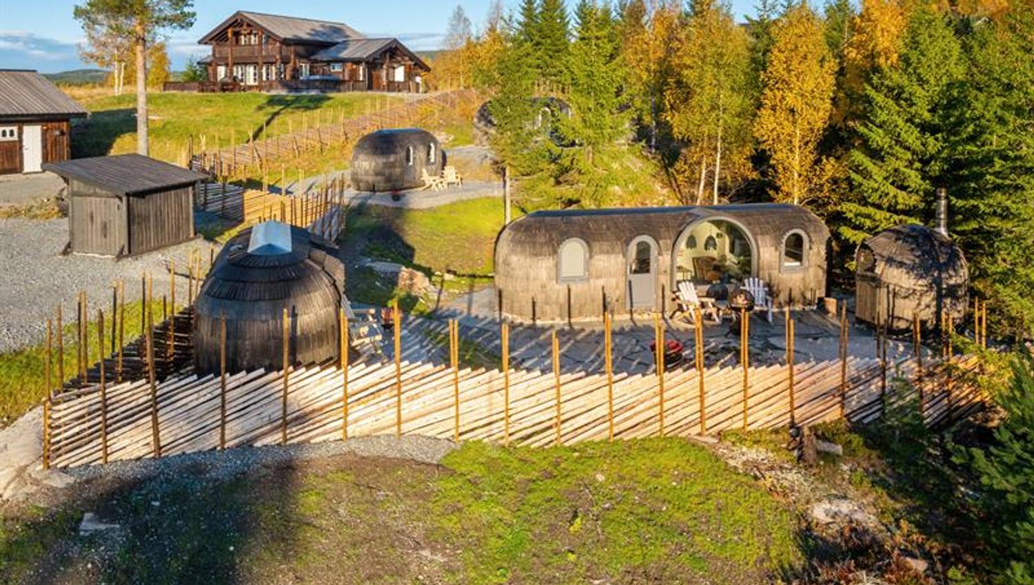 dronebilde av hytter med et gjerde og skog rundt