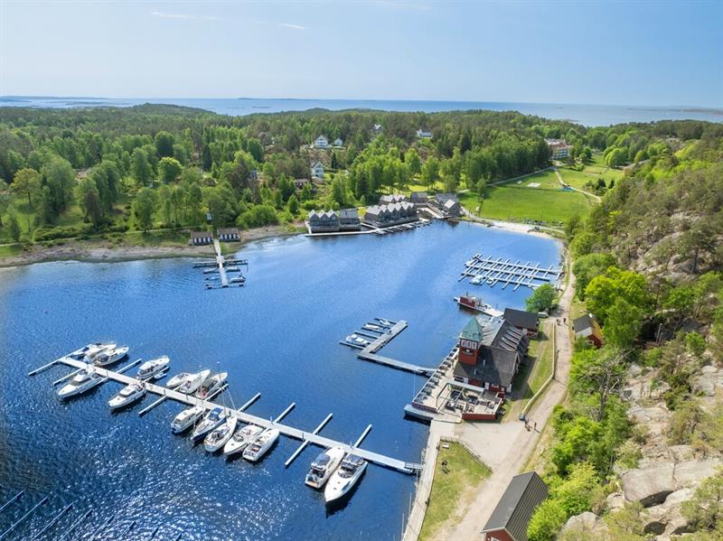 Flyfoto av Hankø med småbåthavn, brygger og båter i naturskjønne omgivelser.
