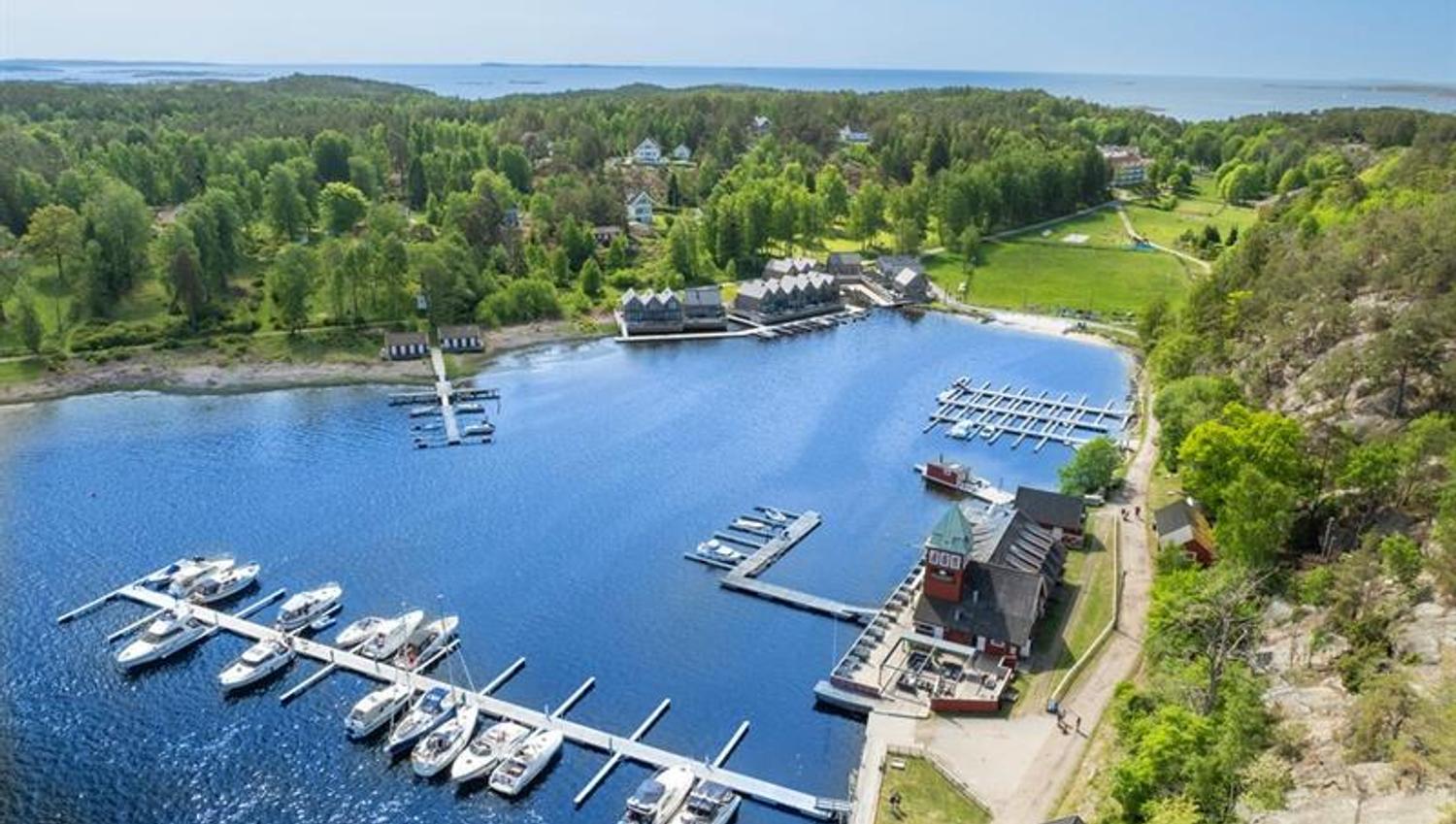 Flyfoto av Hankø med småbåthavn, brygger og båter i naturskjønne omgivelser.