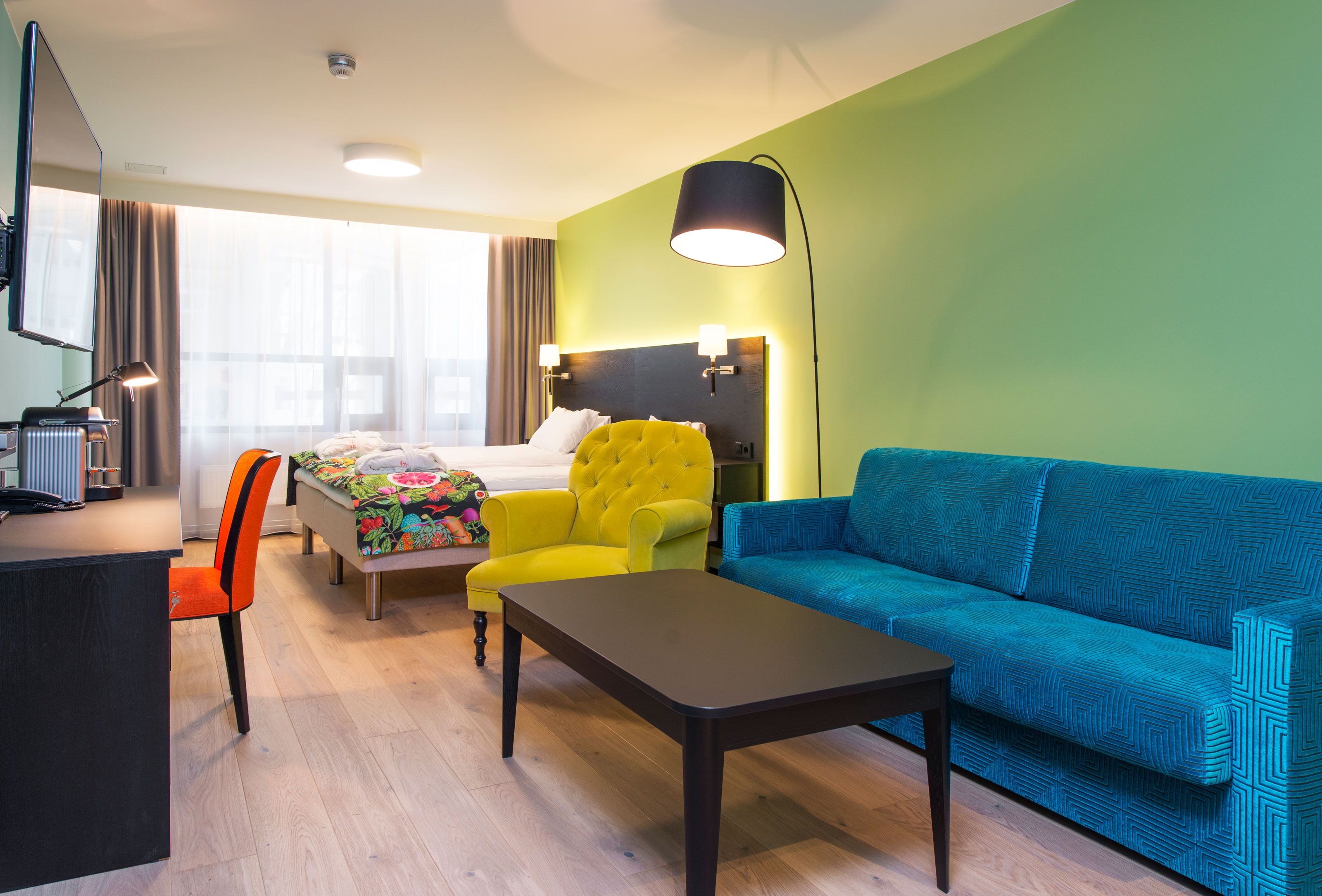 colourful double room with sofa, desk and TV 