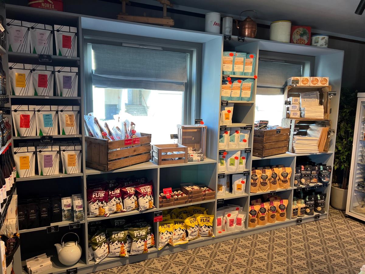 Shelves in a country store filled with a wide variety of foods and products, including jams and dry goods.
