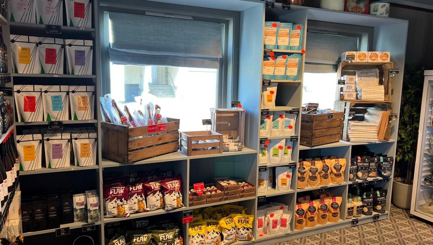 Shelves in a country store filled with a wide variety of foods and products, including jams and dry goods.