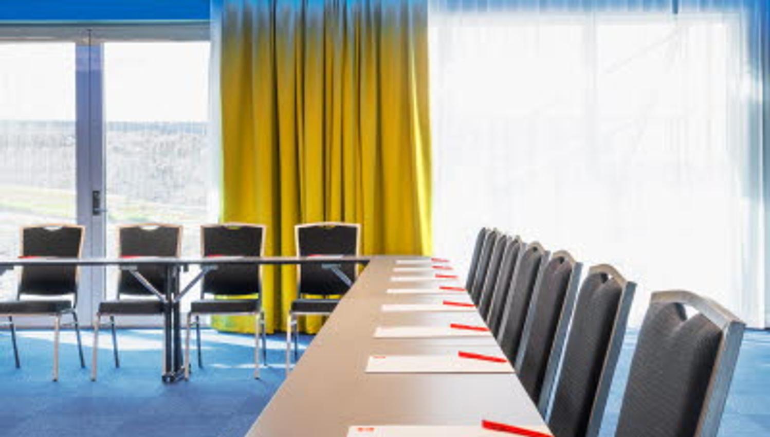Interior of conference room with chairs, table and large panoramic windows.