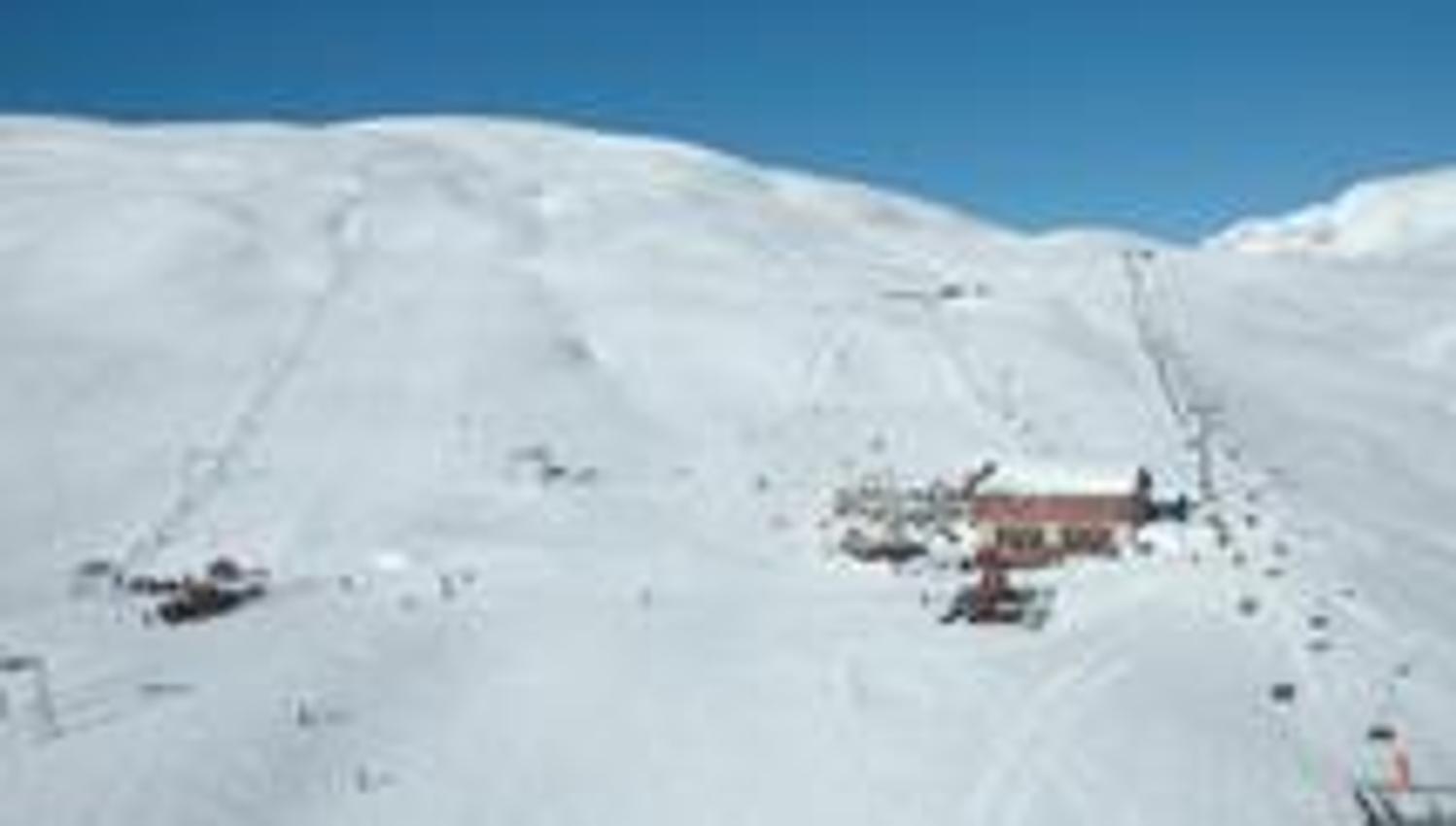 Hauptgebäude und Skilifte im Røldal Skigebiet, umgeben von schneebedeckten Bergen.