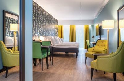 Room interior with double bed, yellow armchairs, table and yellow curtains.
