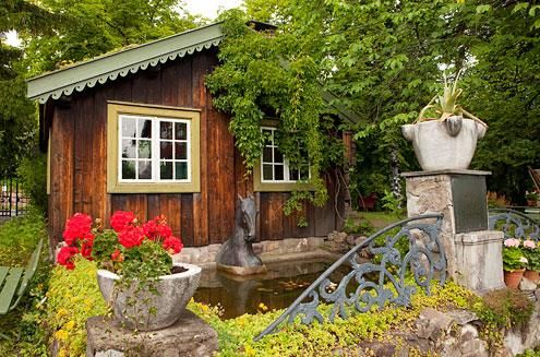 Hus i barokkhagen, smijernsport og røde blomster