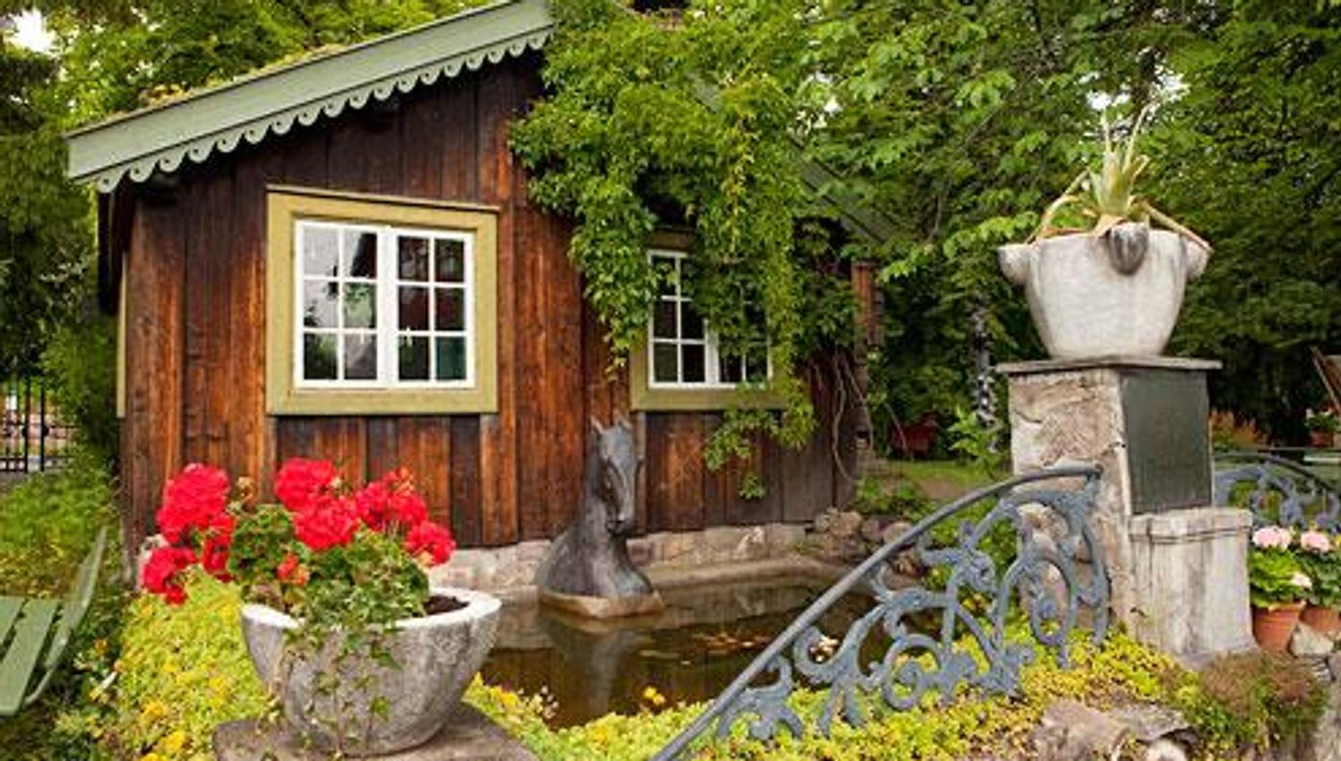 Hus i barokkhagen, smijernsport og røde blomster