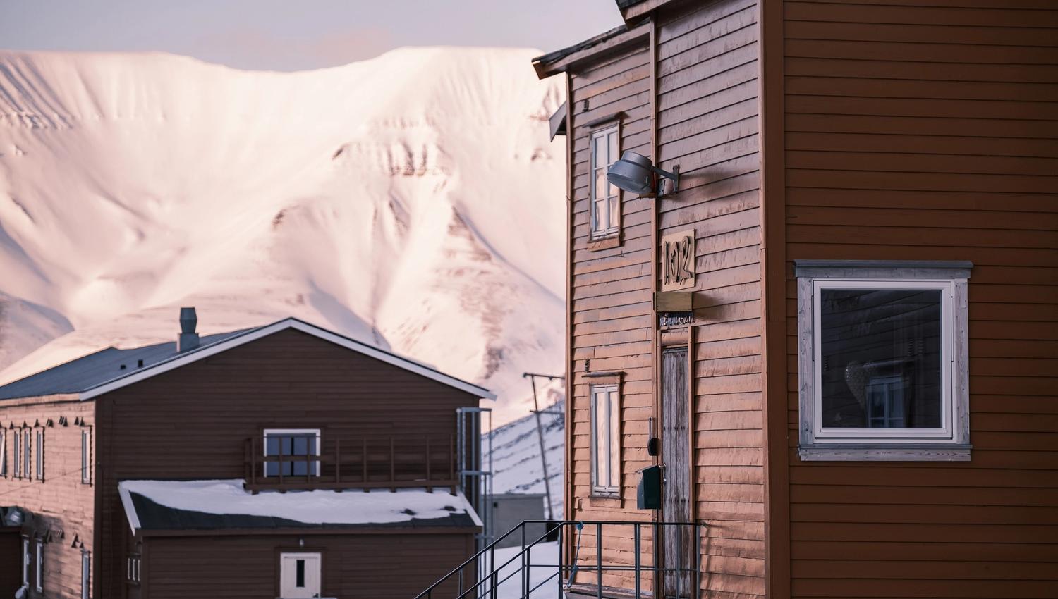The guesthouse in the foreground with another building and a mountain in the background