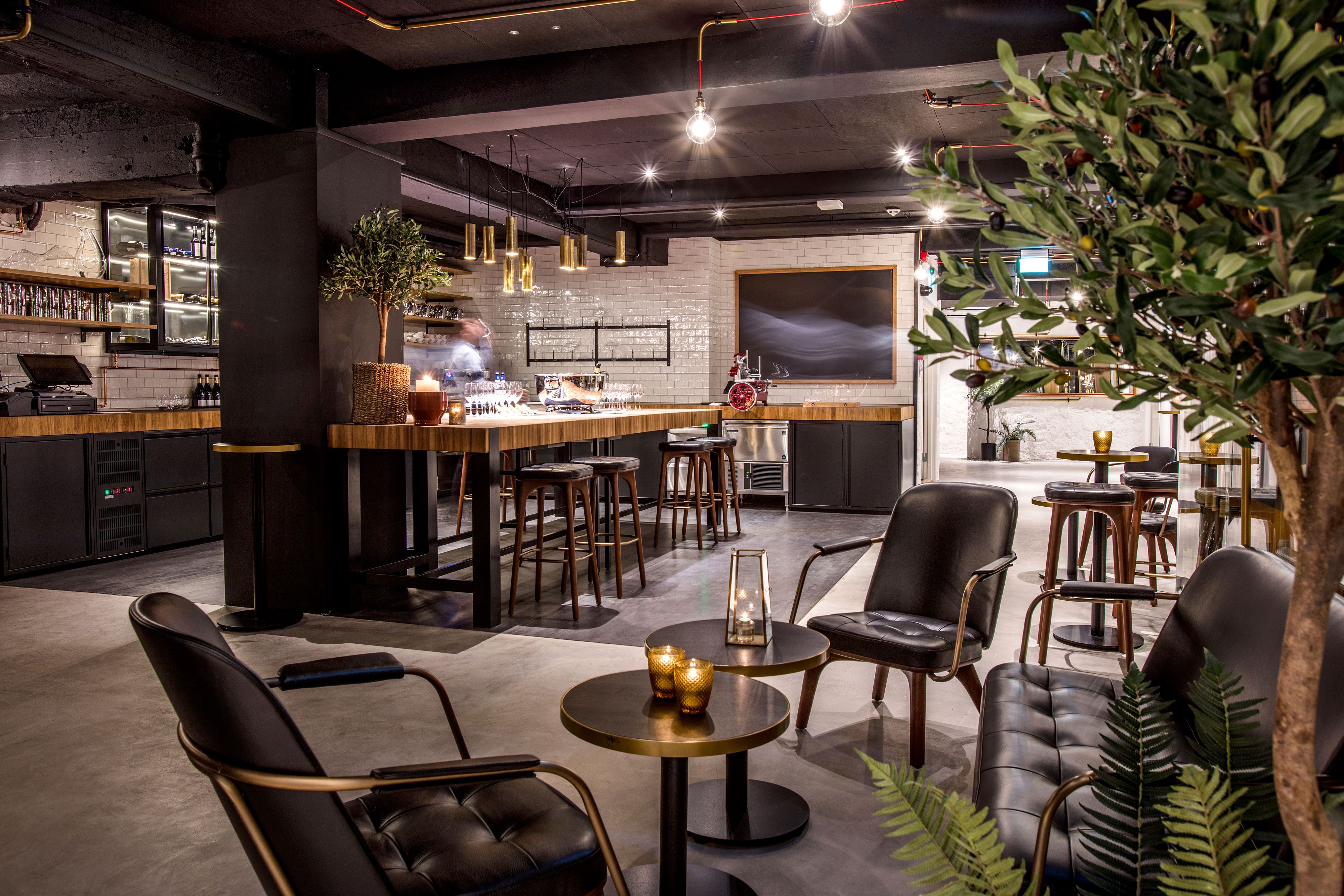 Cozy and elegant seating section with small tables and armchairs, and a potted plant.