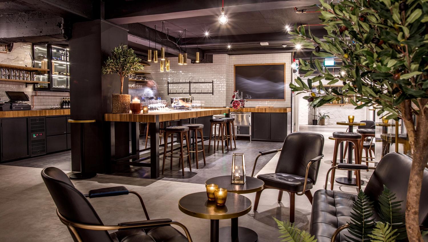 Cozy and elegant seating section with small tables and armchairs, and a potted plant.