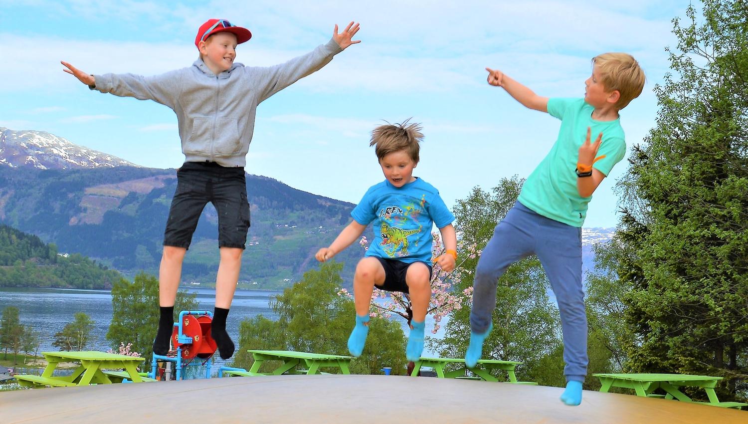 Born hoppar og kosar seg på trampolinen med fjordutsikt i Mikkelparken