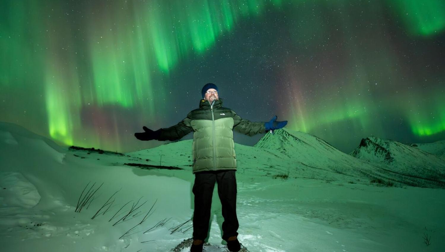 A guest is surrounded by the Aurora Borealis