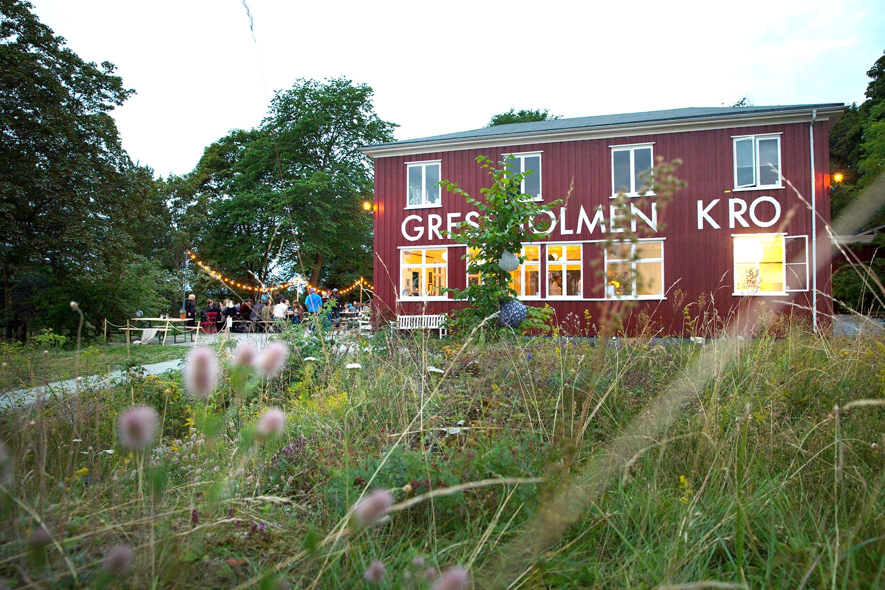 Exterior of Gressholmen Kro with outdoor seating, surrounded by forest.