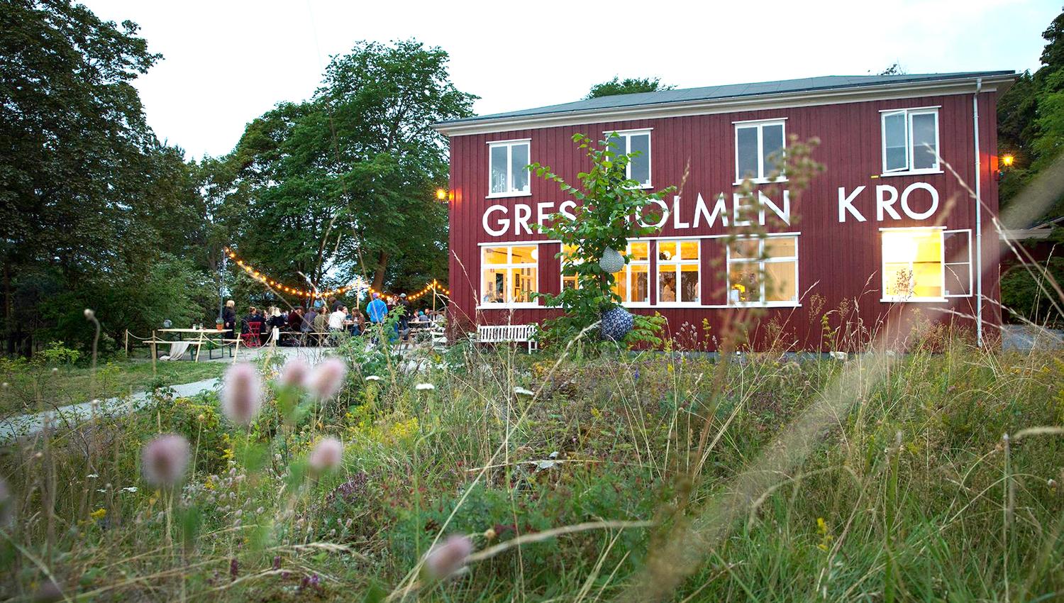Exterior of Gressholmen Kro with outdoor seating, surrounded by forest.