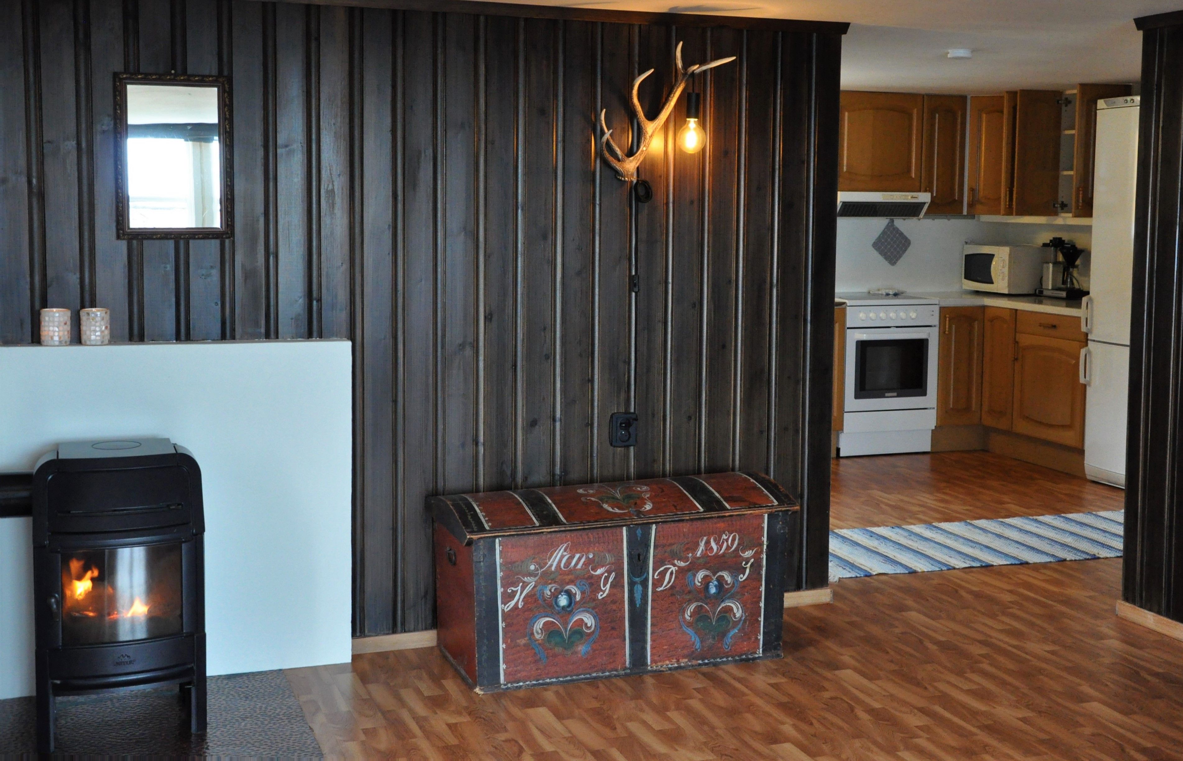 A kitchen in the background and a living room with a fireplace in the foreground 