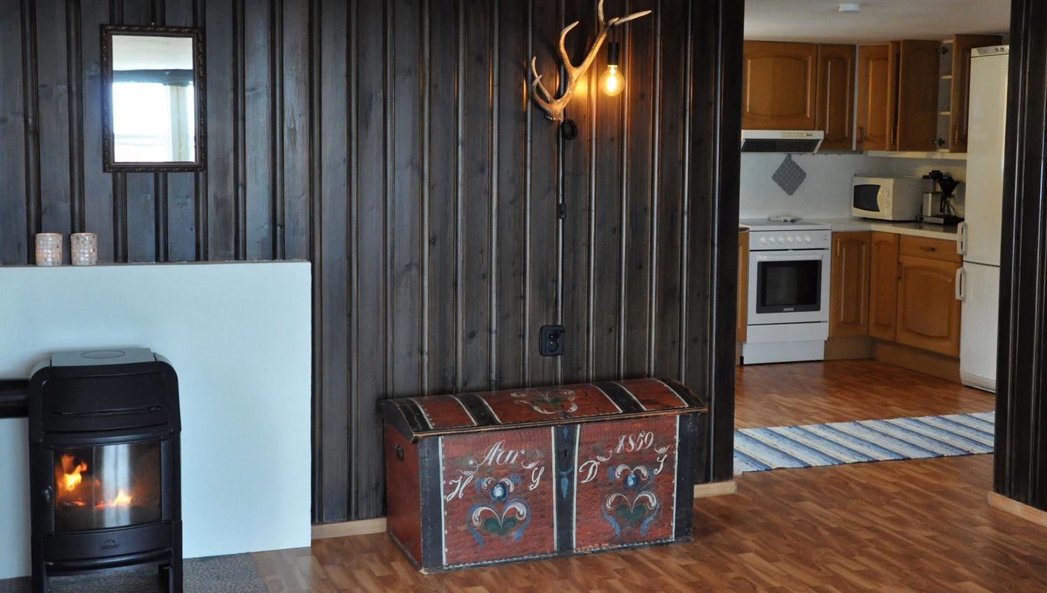 A kitchen in the background and a living room with a fireplace in the foreground