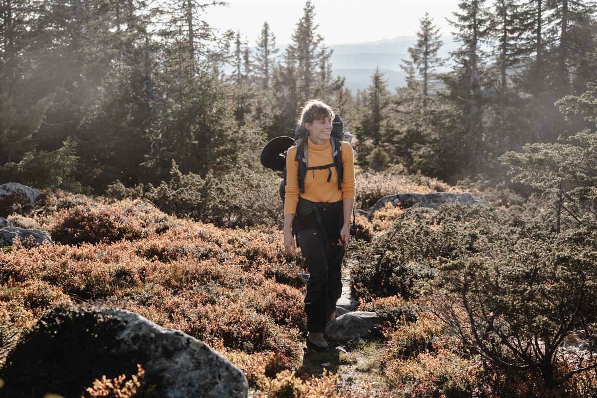 Person walking on a trail in forest and mountain terrain