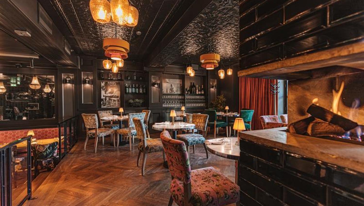 Interior with a fireplace, small tables and chairs.