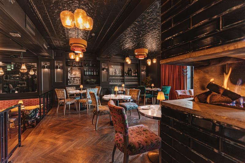 Interior with a fireplace, small tables and chairs.