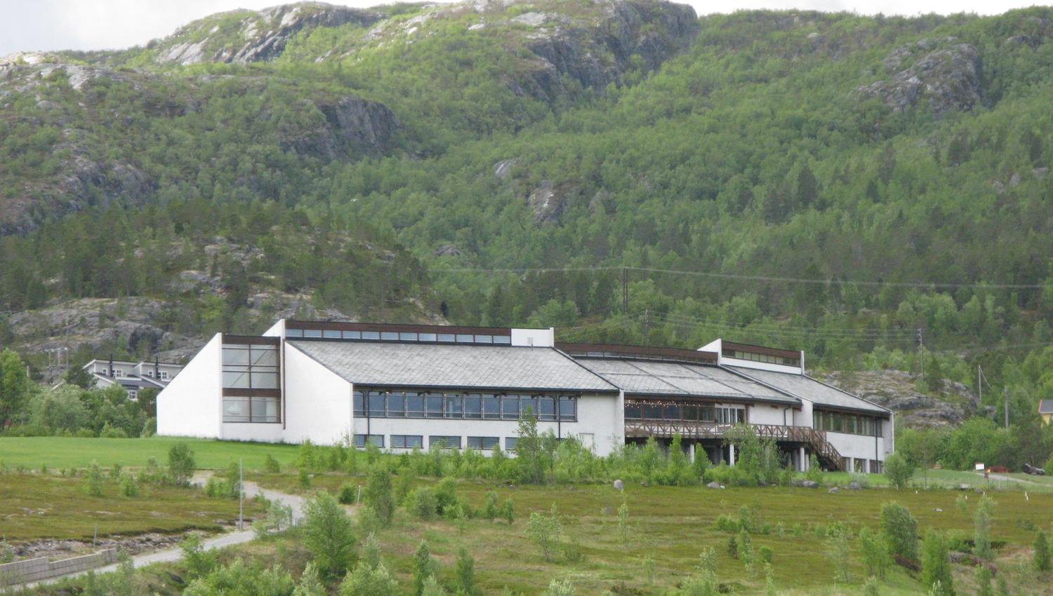 Discover this stunning modern architecture set against a backdrop of lush green hills and rocky terrains, perfect for nature lovers and architecture enthusiasts alike. Enjoy the serene surroundings and experience the beauty of the landscape.