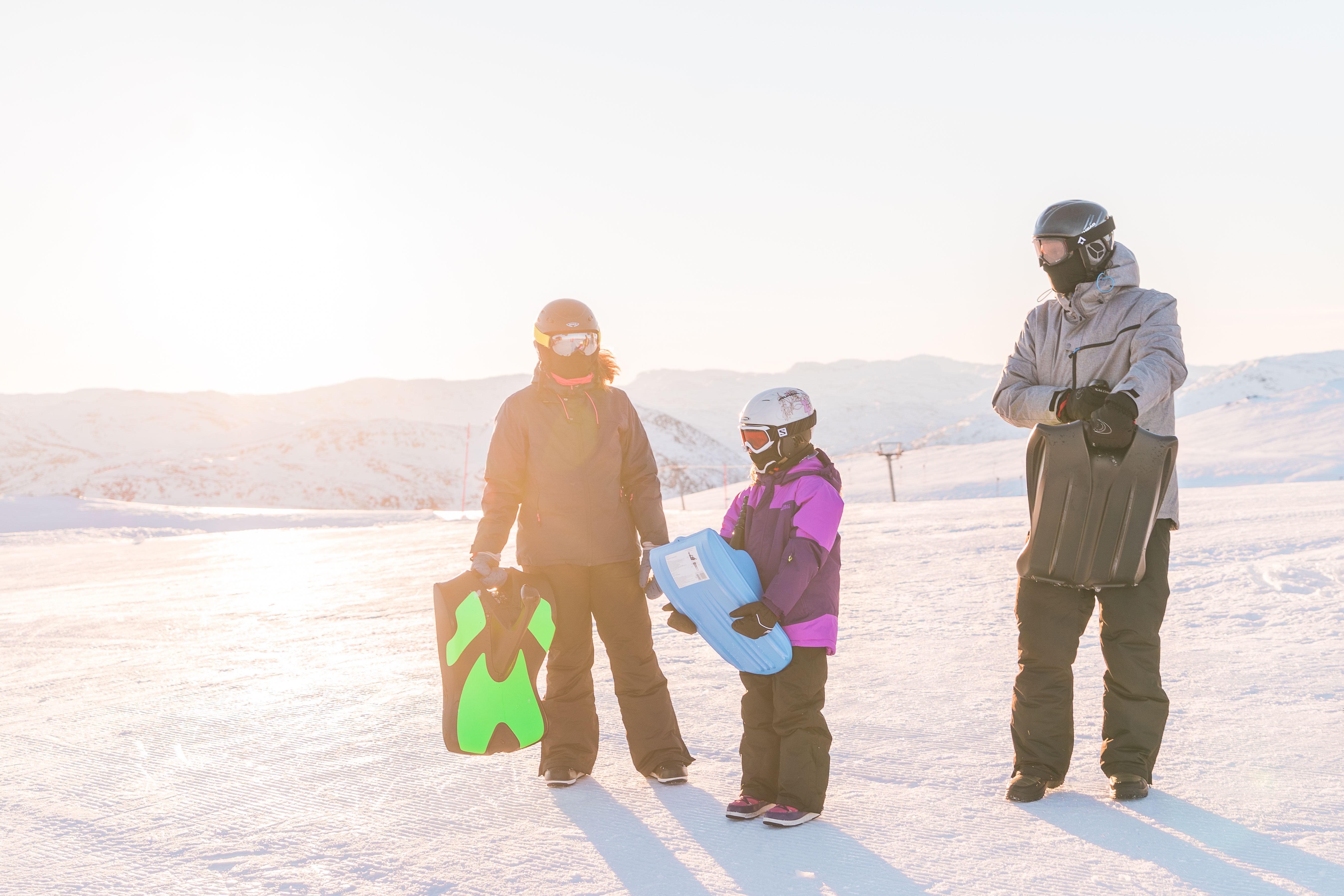 Family of three carrying their sleds, photo